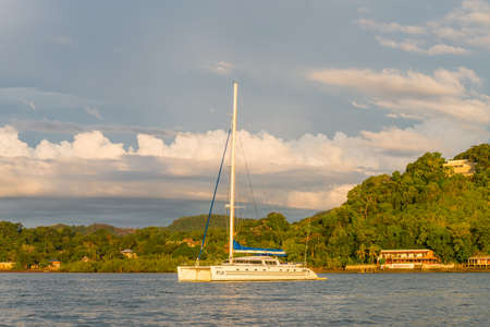 Hell-Ville, Madagascar - December 19, 2015: Catamaran Dragonfly Fiji in the rays of the setting sun anchored at Andavakotakona Bay, near Hell-Ville, Nosy Be Island, Madagascar.のeditorial素材
