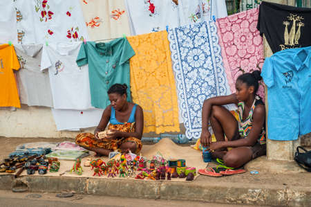 Hell-Ville, Madagascar - December 19, 2015: Indigenous women sell colorful embroidered tablecloths, fabrics and souvenirs on the road at the Hell-Ville (Andoany), Nosy Be Island, Madagascar.のeditorial素材