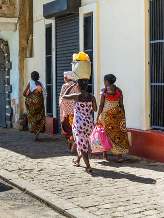 Antsiranana, Madagascar - December 20, 2015: Unidentified Malagasy women walk and carry bags on their heads and a baby on a back in Antsiranana (Diego Suarez), Madagascar, Africa.のeditorial素材