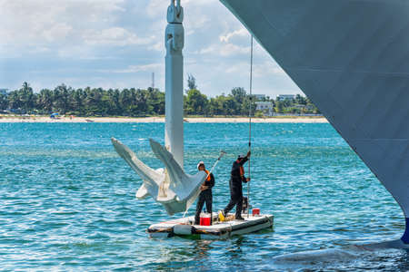Toamasina, Madagascar - December 22, 2017: Two workers clean and make maintenance service to the anchor of a passenger ship moored at Toamasina, Madagascar, East Africa.のeditorial素材
