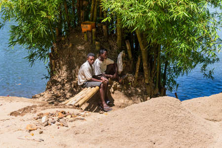 Toamasina, Madagascar - December 22, 2017: Unidentified Madagascar men - Loaders of sand rest on the river bank near the city of Toamasina (Tamatave), Madagascar, East Africa. Everyday life on the river.のeditorial素材