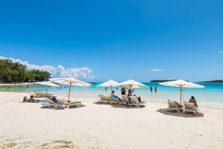 Blue Bay, Mauritius - December 27, 2015: People relax under umbrellas and in the sun on the tropical Blue Bay beach, Mauritius Island. Idyllic travel background.のeditorial素材