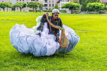 Interlaken, Switzerland - May 26, 2016: Paraglider carries a paraplane after landing on the ground in Interlaken, Switzerland.のeditorial素材