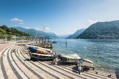 Como, Italy - May 27, 2016: Boats on the shore of Lake Como, city of Como, Italy. Swans on the lake.のeditorial素材