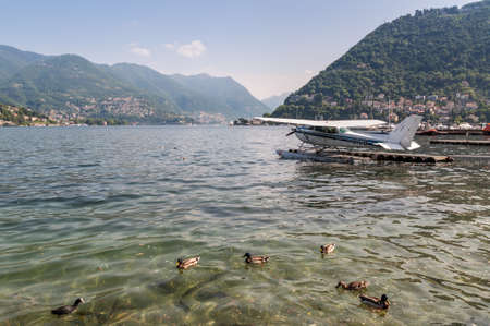 Como, Italy - May 27, 2016: A seaplane docking on at water aerodrome of Como lake in Como City, Italy. Ducks in the foreground.のeditorial素材