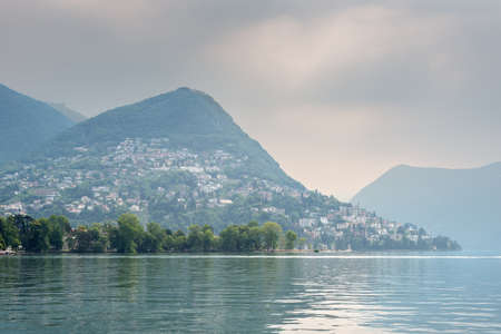 Lake Lugano, mountain Monte Bre in a haze in cloudy rainy weather. Lugano is the largest city of the Swiss canton of Ticino.の写真素材