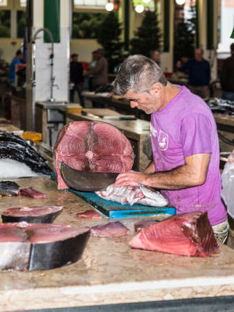 Funchal, Portugal - December 10, 2016: Seller of fish in the Funchal Fish Market Mercado dos Lavradores in Madeira Island, Funchal, Portugal. Selected focus on tuna.のeditorial素材