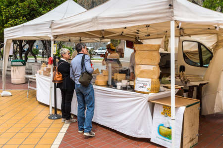 Genoa, Italy - May 14, 2017: Buyers choose cheese in a street shop on the main promenade Corso...