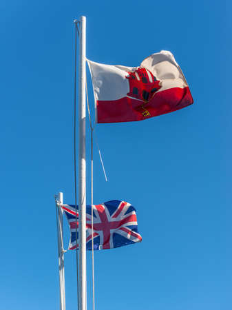 Flags of the Gibraltar and United Kingdom on the Rock of Gibraltar waving on the windの写真素材
