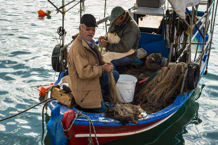 Katakolon, Greece - October 31, 2017: Local fishermen soarting out his nets. Fresh sea food. Catch of the day. Greek local fishermen. Working in the docks on the boat. Aegean lifestyle. seafood. Island life.のeditorial素材
