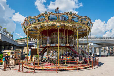 Kyiv, Ukraine - July 13, 2019: Old vintage carousel attraction at Postal Square in Kyiv, Ukraine. Ships moored on the banks of the Dnipro River.
