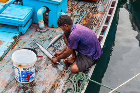 Male, Maldives - November 16, 2017: Area of fresh fish market in cloudy weather in Male, Maldives. A fisherman cleans the fish from the scales on a boat for lunch. Seafood cooking.のeditorial素材