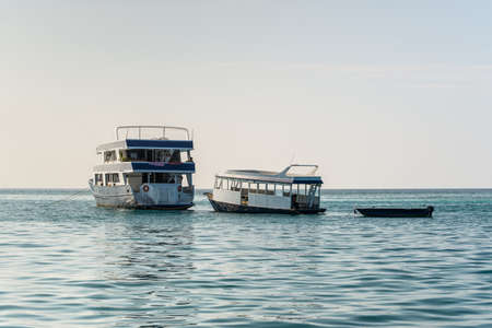 Himmafushi, Maldives - November 18, 2017: Three boats of different sizes are anchored in the sea near the Himmafushi island, Maldives.のeditorial素材