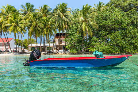 Huraa, Maldives - November 19, 2017: Motor boat anchored on clear turquoise water in the Indian Ocean near the Huraa Island, Maldives. Picturesque landscape with palm trees on the shore.のeditorial素材