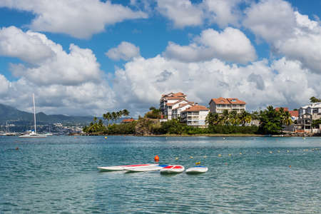 Les Trois-Ilets, Martinique - December 13, 2018: Surfboards (SUP boards) in the foreground of the tropical Anse Mitan Beach at Les Trois-Ilets, peninsula Pointe du Bout, Martinique, FWI.のeditorial素材