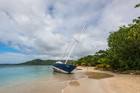 Sainte-Anne, Martinique - December 20, 2018: Abandoned beached sailboat after the hurrican Maria at the beautiful tourist beach at Sainte-Anne in Martinique, Caribean island in cloudy weather.のeditorial素材