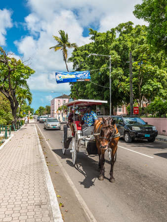 Nassau, Bahamas - May 3, 2019: Street view of Nassau at day with tourists in a horse drawn carriage through town. Nassau sees thousands of visitors daily, the majority of which arrive by cruise ship.のeditorial素材
