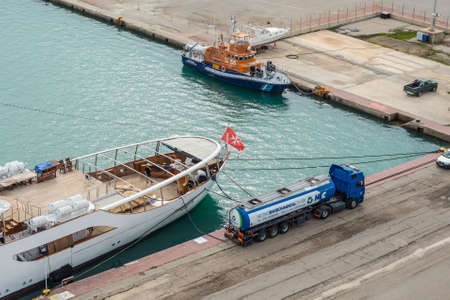 Katakolon, Greece - November 11, 2019: Fuel tanker truck refueling motor yacht Christina O in harbor...