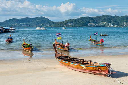 Phuket, Thailand - November 29, 2019: Traditional longtail boats with national flag on the shore of Patong beach at Andaman sea, Phuket island in Thailand.のeditorial素材