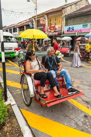 George Town, Penang, Malaysia - December 1, 2019: Classic local rickshaw with tourists in cloudy...
