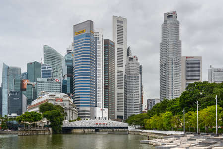 Singapore - December 3, 2019:  Singapore skyscrapers with Anderson bridge, Fullerton Hotel  and a few towers of financial district near Esplanade Park. Some green foliage on both sides.のeditorial素材