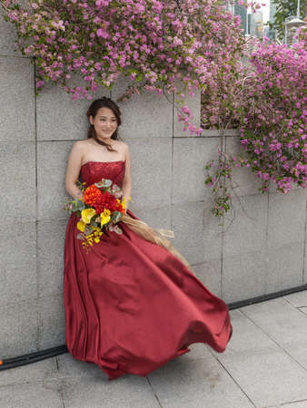 Singapore - December 3, 2019: Outdoor portrait of young and beautiful asian bride with bouquet in hand standing on the waterfront in Singapore.のeditorial素材