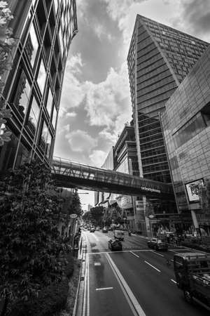 Singapore - December 4, 2019: Orchard Gateway glass bridge crossing over Orchard Road into Orchard Central shopping mall with cars and traffic driving along the road in Singapore. Black and white.のeditorial素材