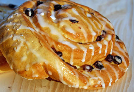 Delicious and flavorful sugar bun with raisins on wooden tableの写真素材