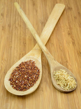 Raw Quinoa and Brown Rice in wooden spoons against a bamboo background の写真素材