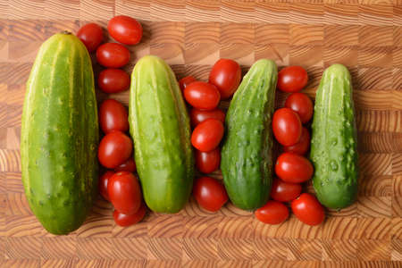 Cucumbers and Tomatoes on a wood cutting board の写真素材