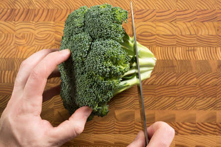 Someone cutting broccoli on a cutting board.の写真素材