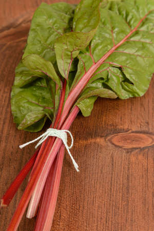 A bunch of swiss chard tied together on a wood table.の写真素材