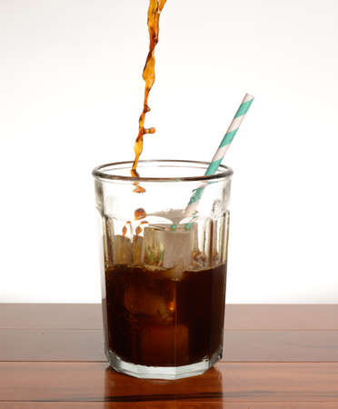 coffee being poured into a glass filled with iceの写真素材