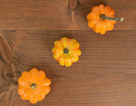 Three mini pumpkins viewed from above and on a wood tableの写真素材