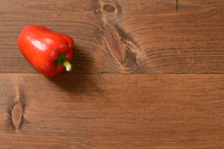 A single ripe red pepper on a wood table.の写真素材