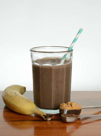 Chocolate banana smoothie in a glass on a wooden table.の写真素材