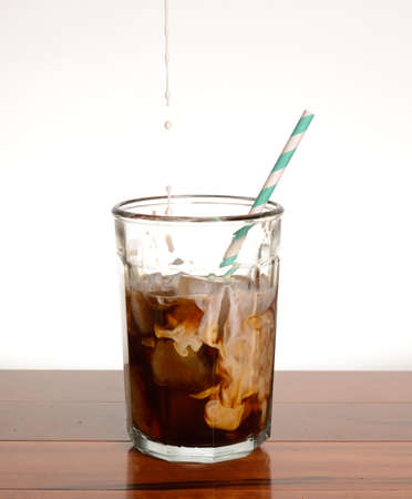 Cream being added to a glass of ice coffee.の写真素材
