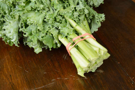 A closeup of a bunch of kale on a wood table.の写真素材
