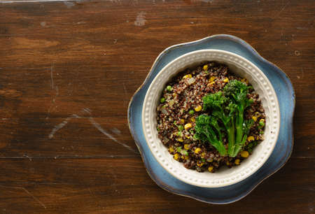 Quinoa bowl filled with broccoli, corn, peas, and onionsの写真素材
