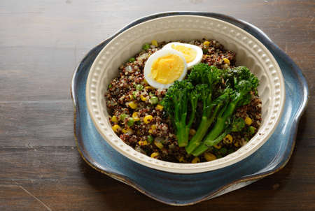 Quinoa bowl filled with broccoli, corn, peas, and hard boiled egg.の写真素材