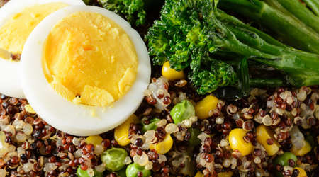 A close up of a quinoa bowl with broccoli, egg, corn, and peasの写真素材