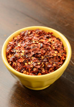 Crushed red pepper flakes in a yellow bowl.の写真素材