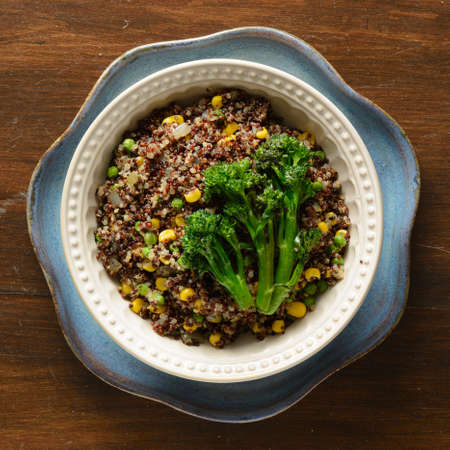 Quinoa bowl filled with broccoli, corn, peas, and onionsの写真素材