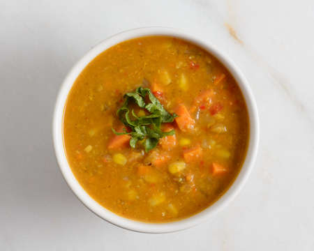 Warm sweet potato and corn soup in a white bowl on a marble backgroundの写真素材