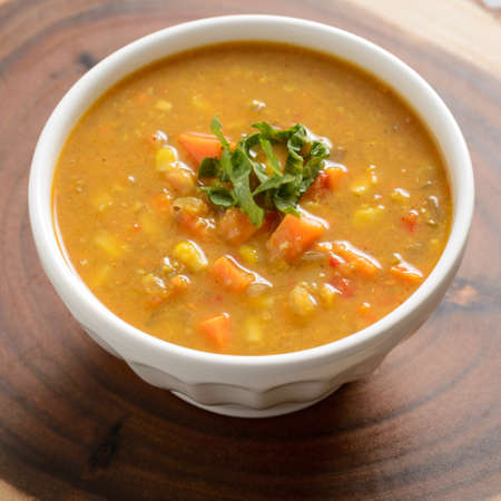 Warm sweet potato and corn soup in a white bowl on a wood backgroundの写真素材