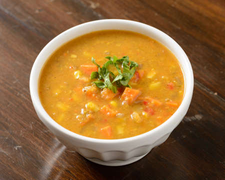 Warm sweet potato and corn soup in a white bowl on a wood backgroundの写真素材