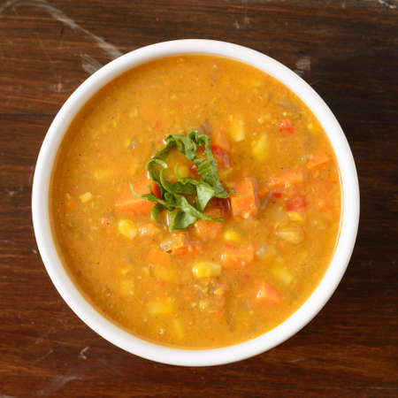 Warm sweet potato and corn soup in a white bowl on a wood backgroundの写真素材