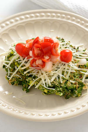 Pan fried spinach fritters platted and topped with cherry tomatoes and shredded cheese.の写真素材