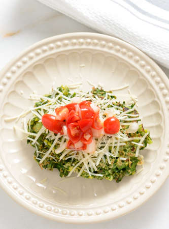 Pan fried spinach fritters platted and topped with cherry tomatoes and shredded cheese.の写真素材