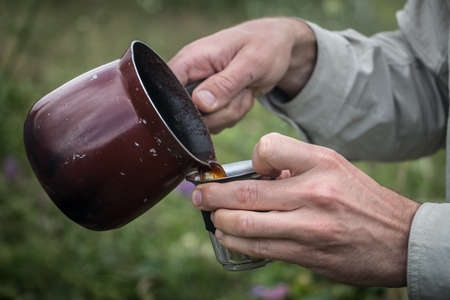 Man pouring coffee into cup in natureの写真素材